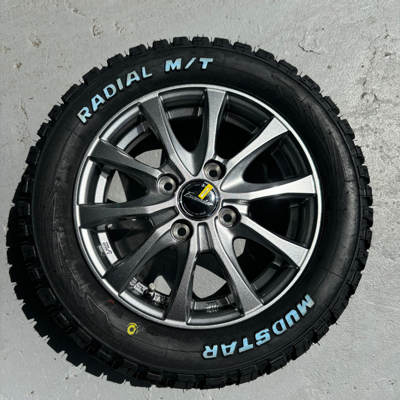Load image into Gallery viewer, A silver alloy wheel fitted with 13&quot; Mudstar Radial M/T tyres on a concrete background
